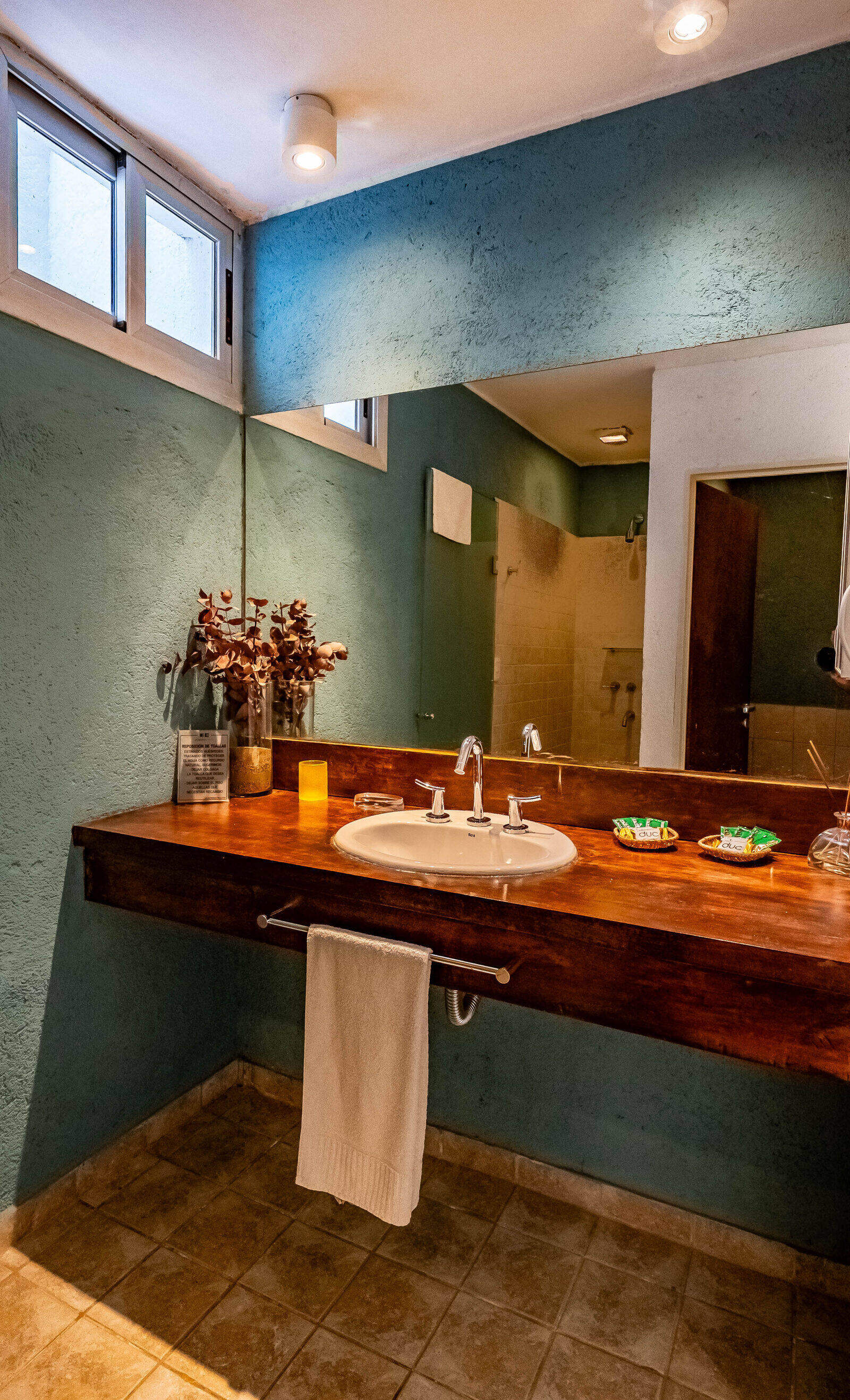 Baño de la casa con bacha sobre mesada de madera y velas encendidas
