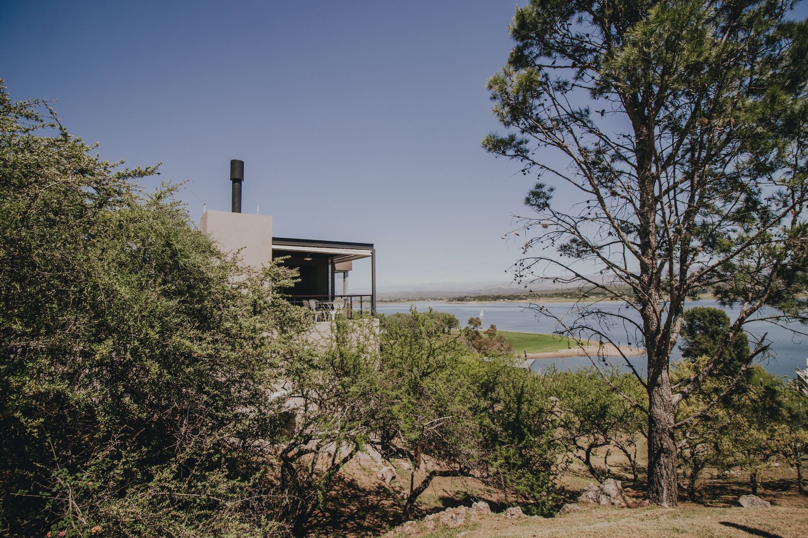 Casa con chimenea entre el monte serrano, con el lago de fondo