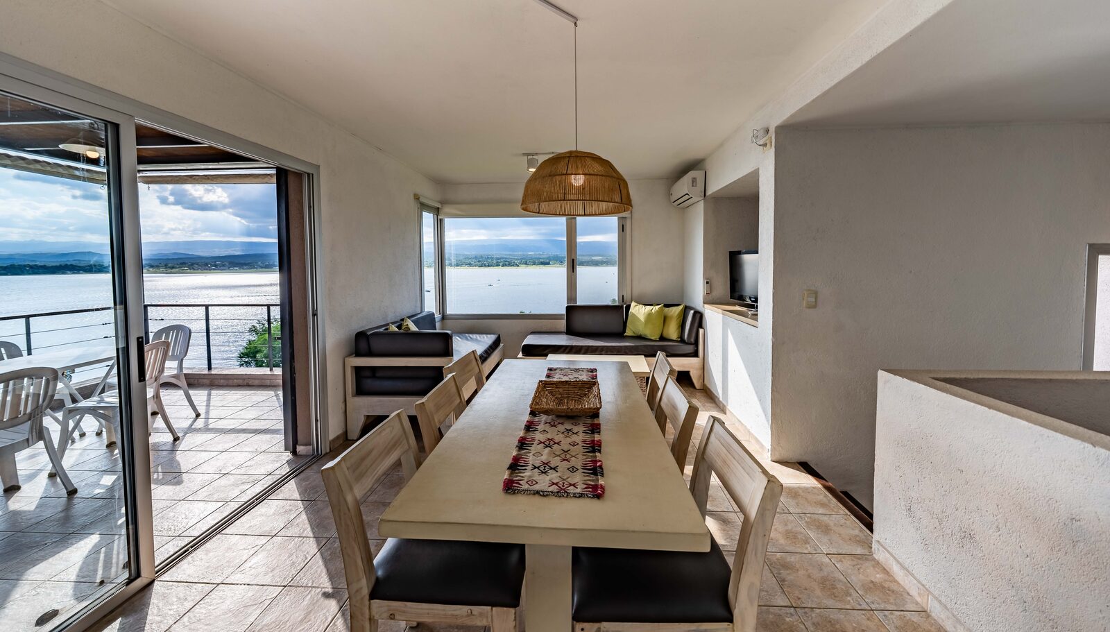 La mesa larga de la casa con el lago y la galería de fondo