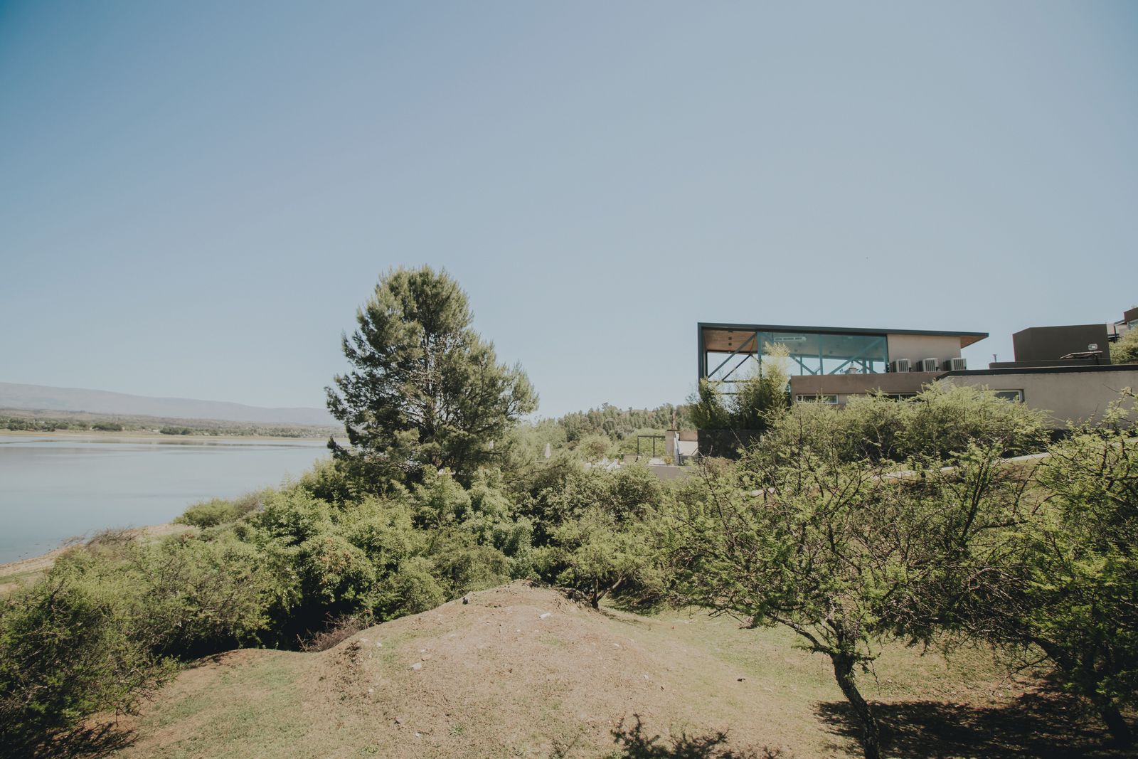 Casa de Lago vidriada sobre la loma, con el Lago Los Molinos detrás