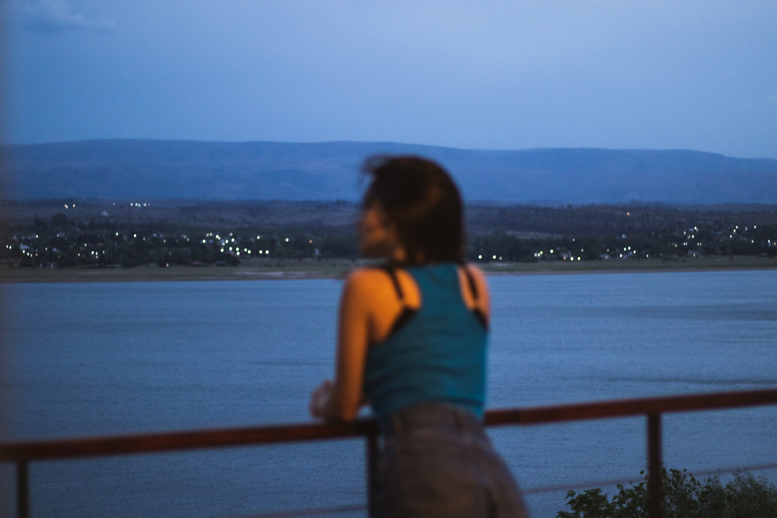 Uma pessoa olhando o lago do guarda-corpo, ao entardecer