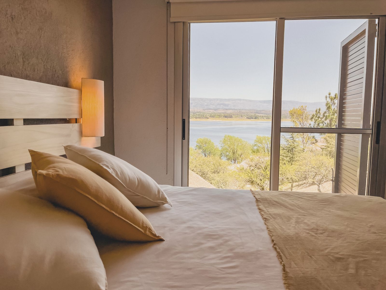 Dormitorio soleado de una Casa de Lago con el lago por la ventana
