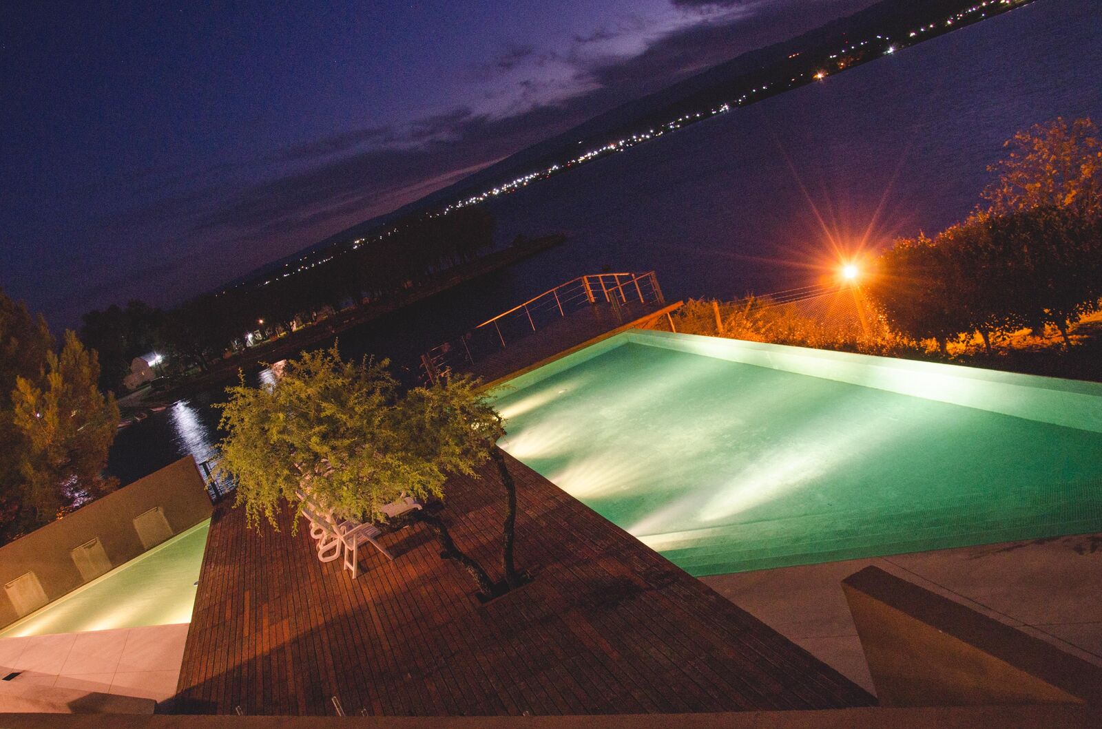 A piscina iluminada à noite, com as luzes do povoado do outro lado do Lago Los Molinos