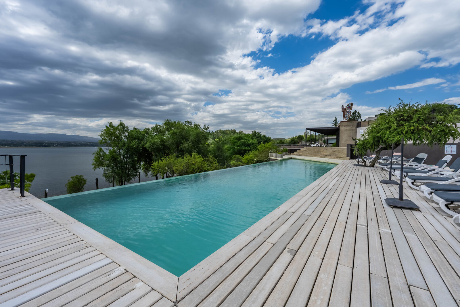 A piscina infinita rente ao lago, com o deck de madeira