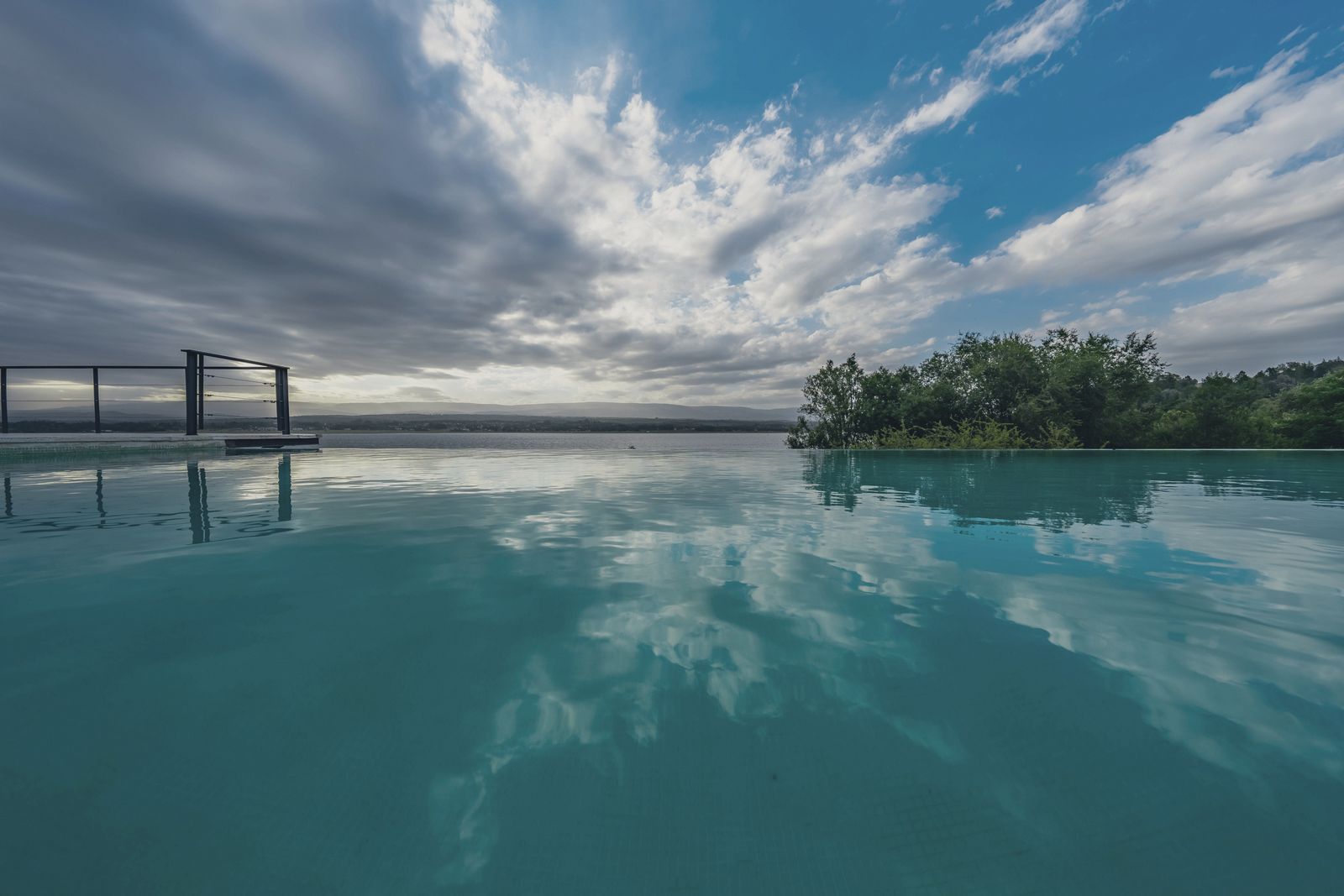 Piscina de borda infinita rente ao Lago Los Molinos com o céu refletido
